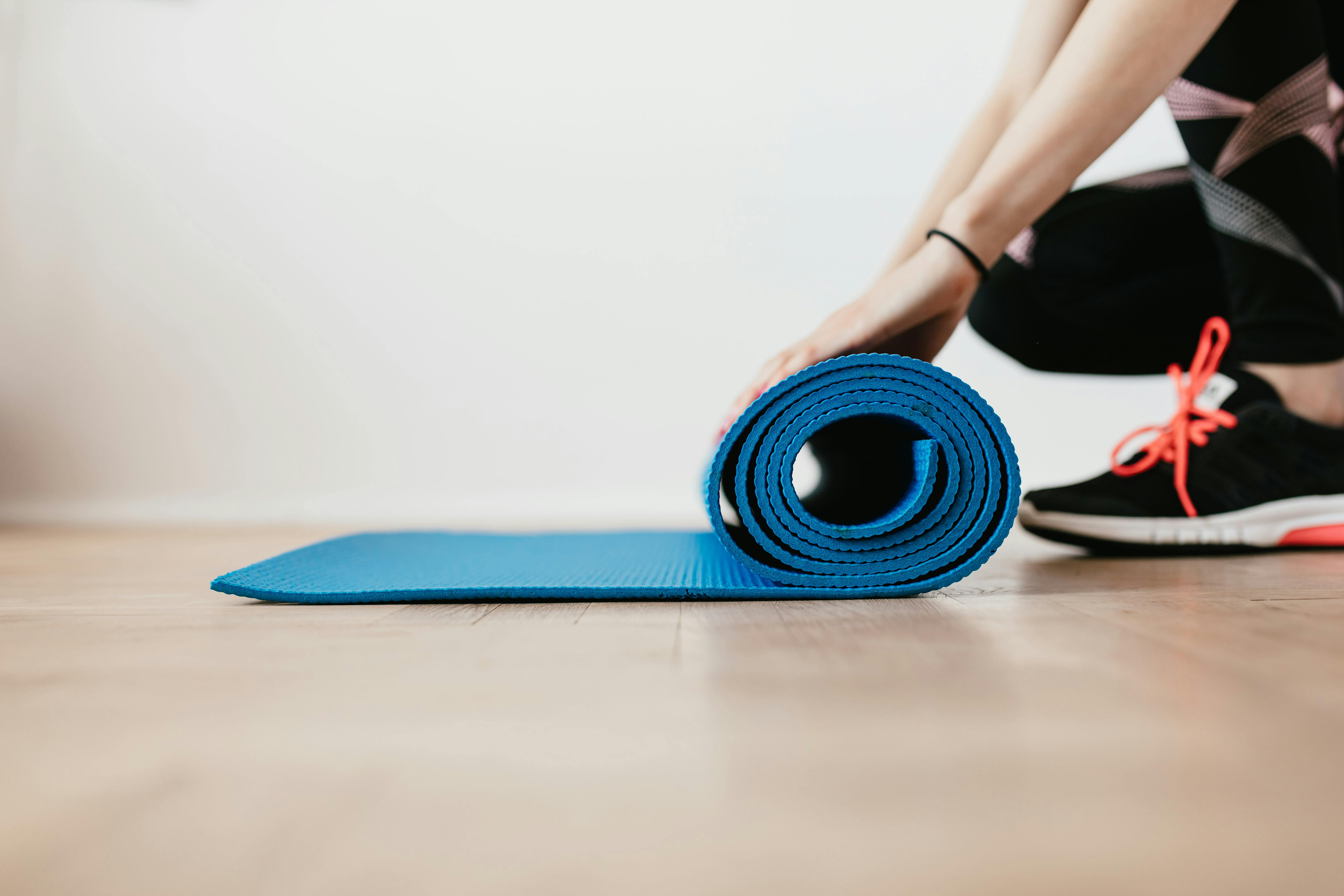 person rolling up an exercise mat